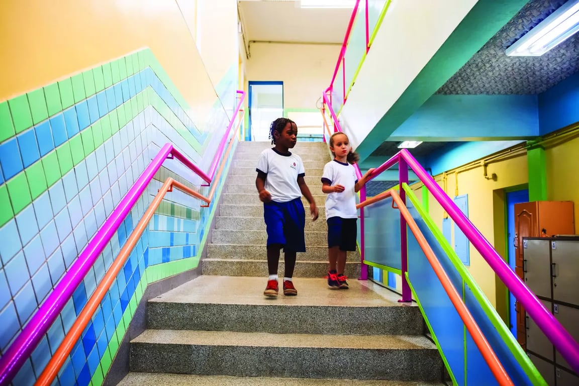 Ambiente escolar público com estudantes e professores em movimento, luz natural e cores vivas