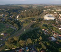 Vista aérea de São Carlos SP ao entardecer, com áreas urbanas e verdes.