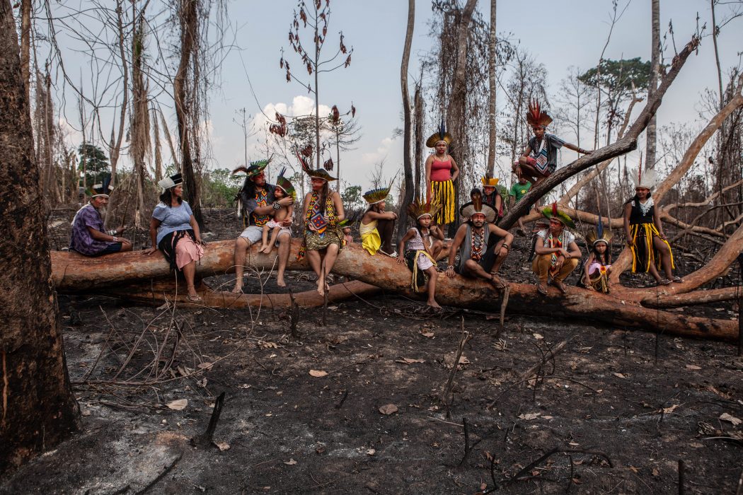 Vista aérea da Amazônia com áreas queimadas e fumaça leve na estação seca, próxima a comunidade ao longo de estrada