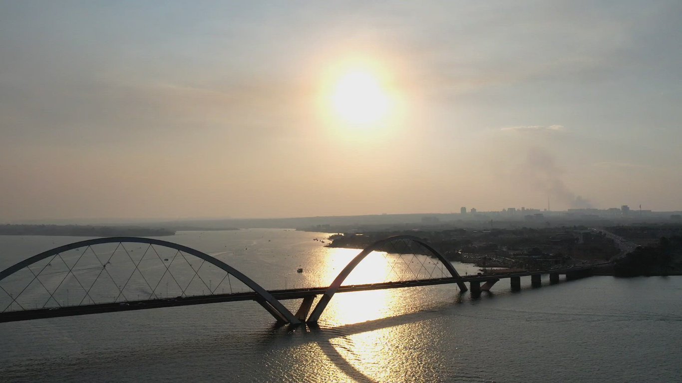 Vista aérea de cidade com rio e ponte ao entardecer
