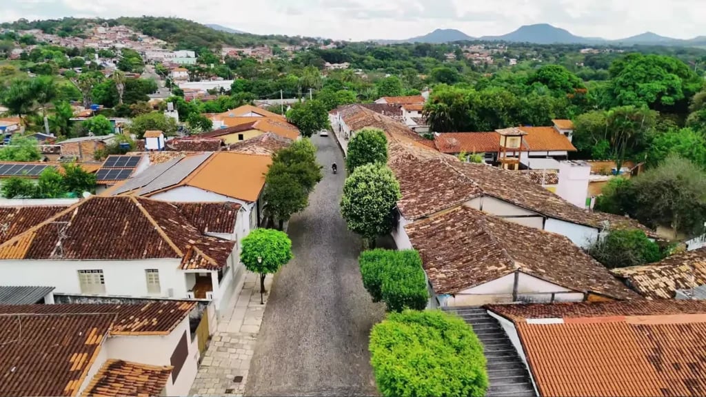 Vista aérea de uma pequena cidade do interior com ruas arborizadas e prédios baixos sob luz de fim de tarde