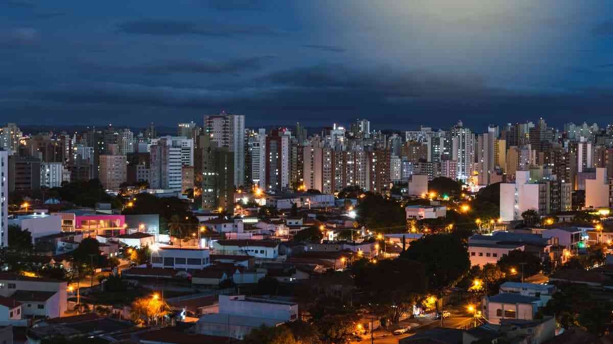 Campinas ao entardecer, com prédios e áreas verdes iluminados pela luz da cidade