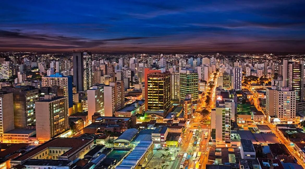 Skyline de Campinas ao entardecer, com tons dourados e prédios iluminados