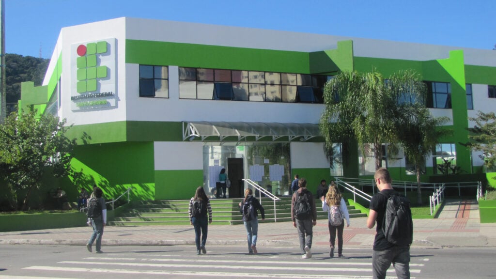 Fachada de instituto federal em Santa Catarina, com estudantes chegando em dia ensolarado