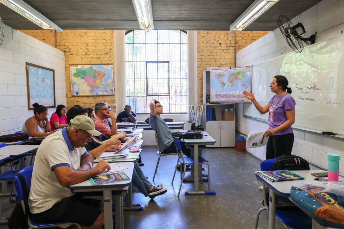 Sala de aula universitária com professora e estudantes, ambiente moderno e genérico