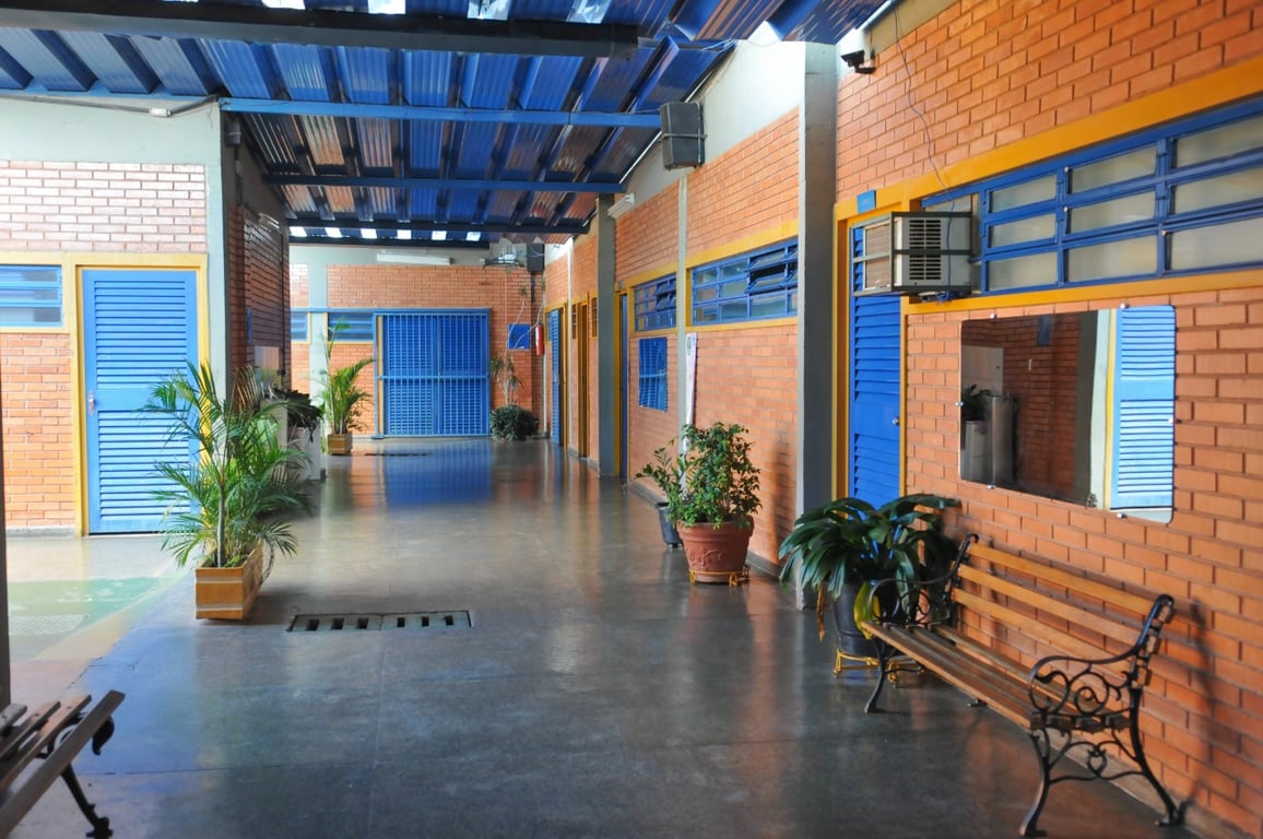 Corredor de escola pública, com carteiras e luz natural