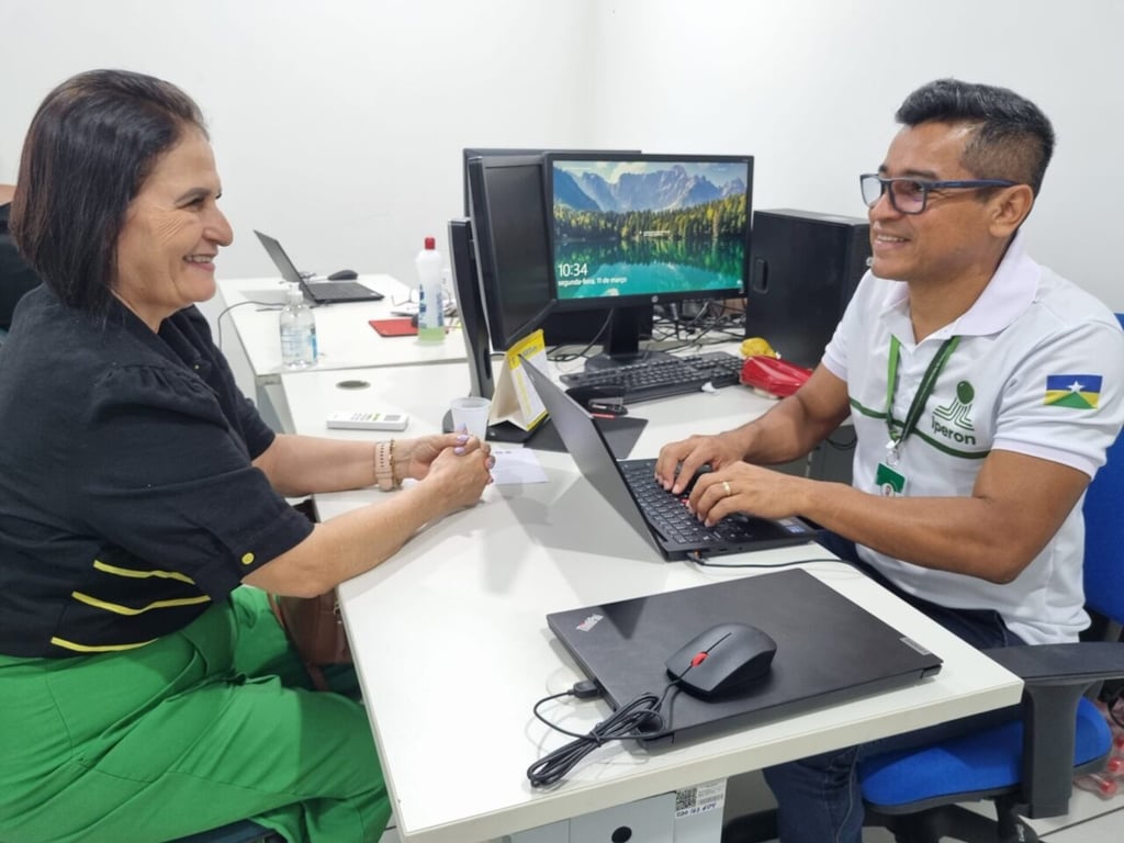 Dois servidores públicos conversam em escritório moderno com computadores e documentos