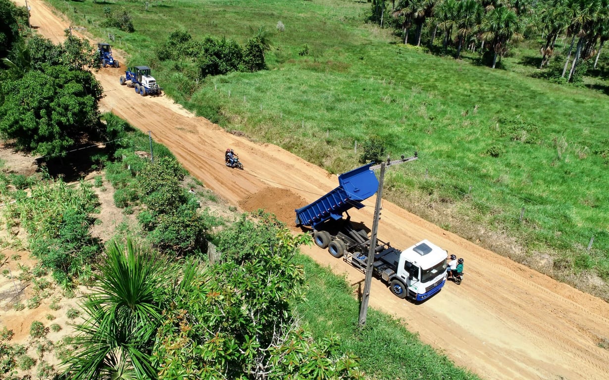 Máquinas pesadas em manutenção de estrada rural, com equipe utilizando EPIs