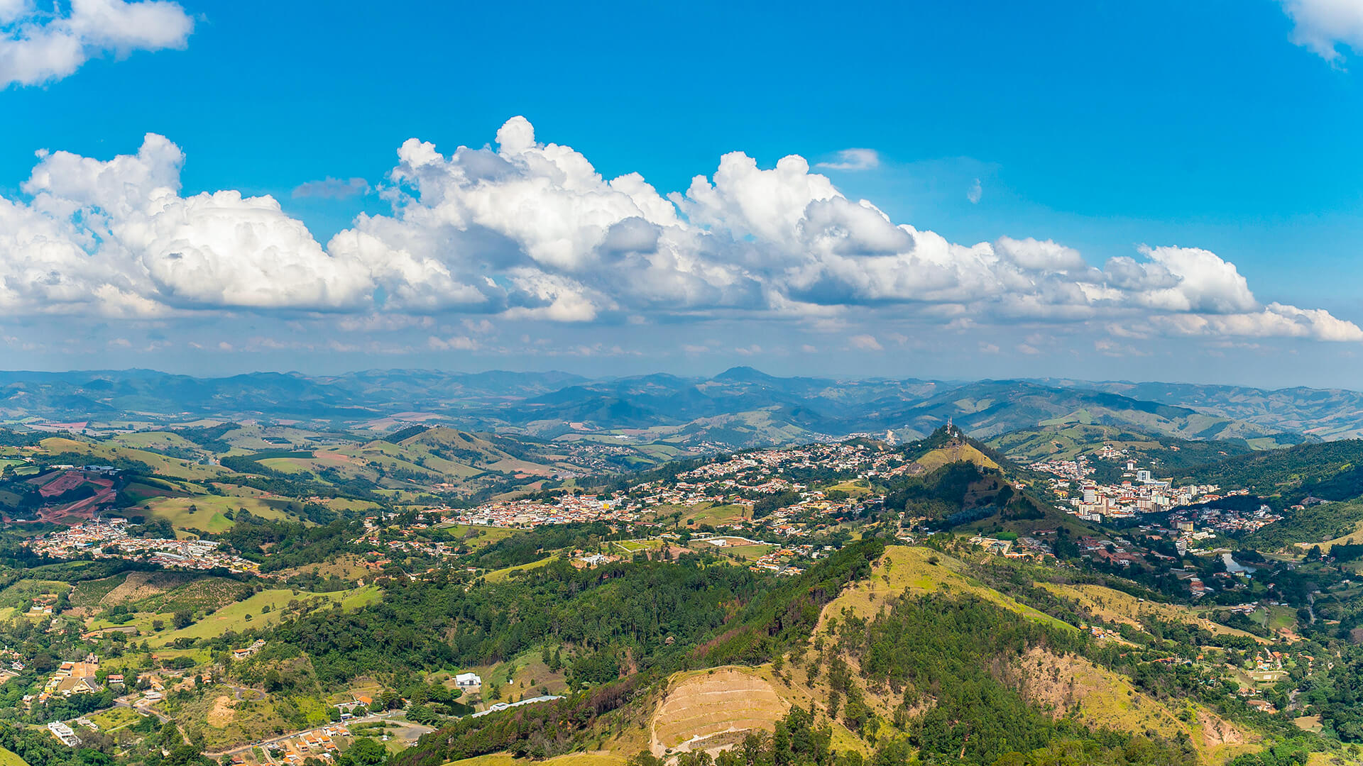 Vista aérea de cidade do interior paulista, com áreas verdes e céu azul, em dia ensolarado
