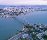 Vista aérea de Florianópolis com a Ponte Hercílio Luz ao fundo ao pôr do sol.