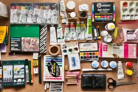Materiais de artes sobre mesa: pincéis, tintas e papéis em ambiente de ateliê