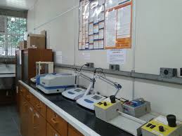 Ambiente universitário de laboratório de química, com vidrarias e equipamentos em bancada