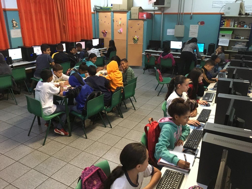 Sala de aula de informática com estudantes e professor