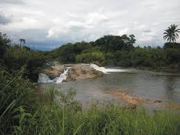 Paisagem do Vale do Ribeira, com rio, vegetação de Mata Atlântica e morros ao fundo, sob céu nublado