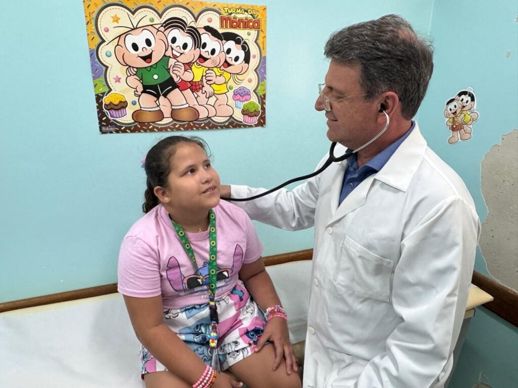Médico ausculta criança em consultório pediátrico, ambiente acolhedor e iluminado
