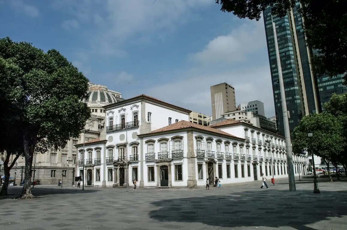Centro do Rio de Janeiro em dia ensolarado, com edifício histórico e pedestres na praça