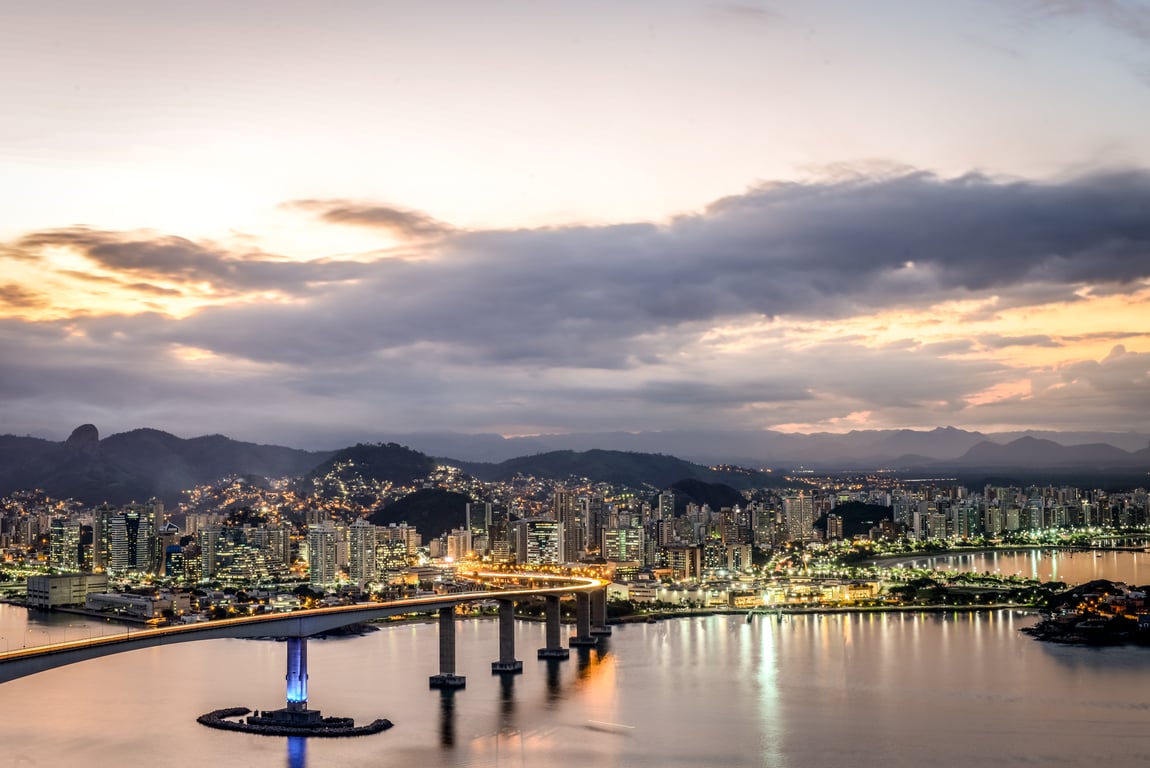Vista aérea de Vitória ES ao entardecer, com a Terceira Ponte ao fundo