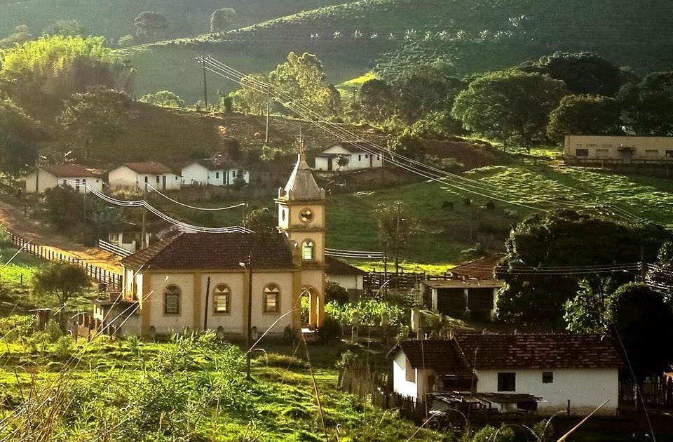 Vista da Zona da Mata mineira, com igreja e morros verdes ao fundo