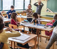Sala de aula do ensino fundamental com alunos e professor ao fundo no Colégio Pedro II.