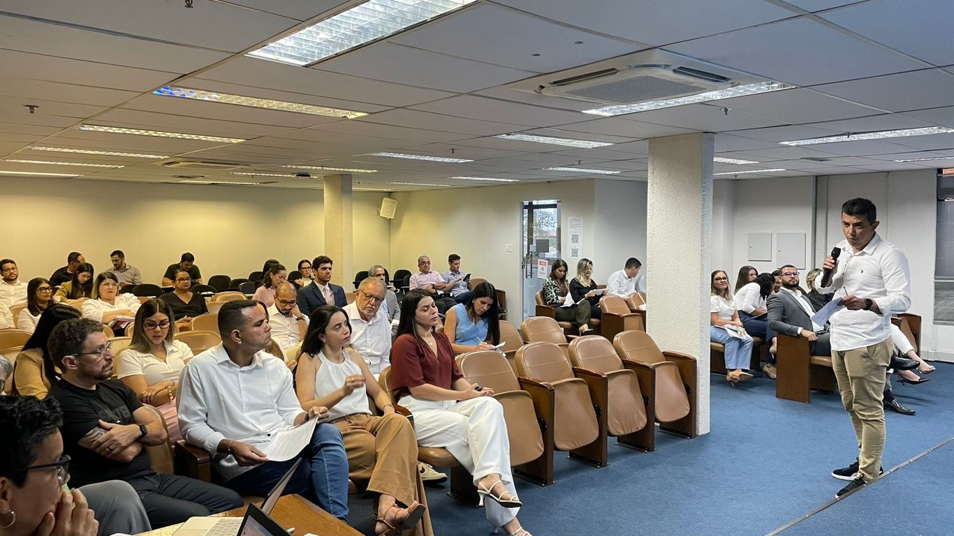 Ambiente de sala de aula com projetor e docente em apresentação didática