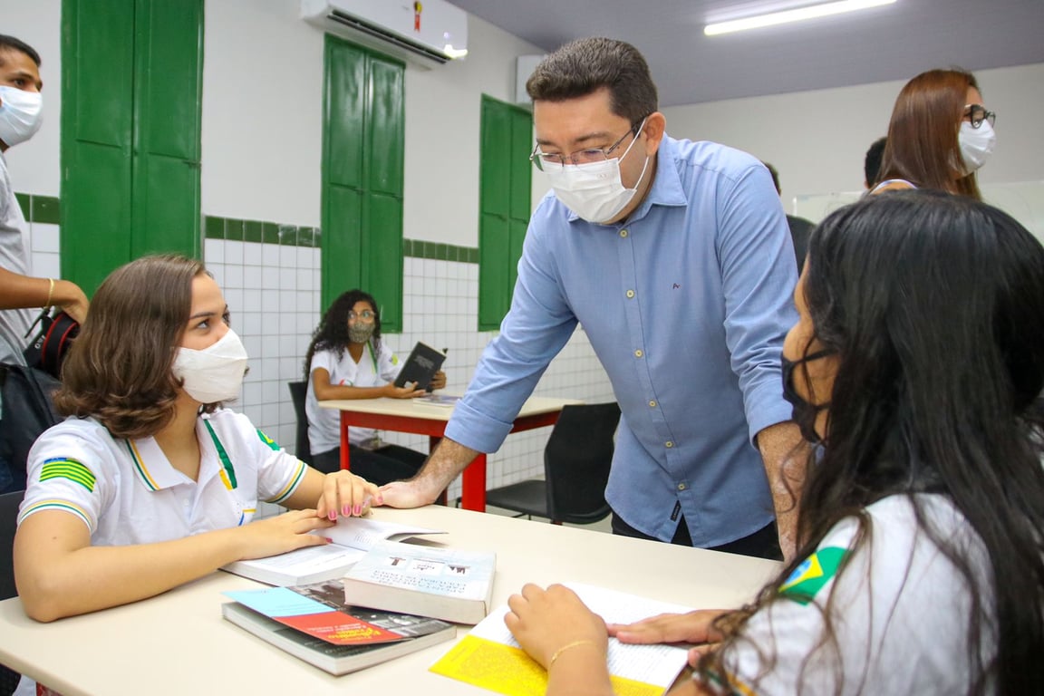 Sala de aula na rede pública com professor e estudantes, ambiente moderno e iluminado