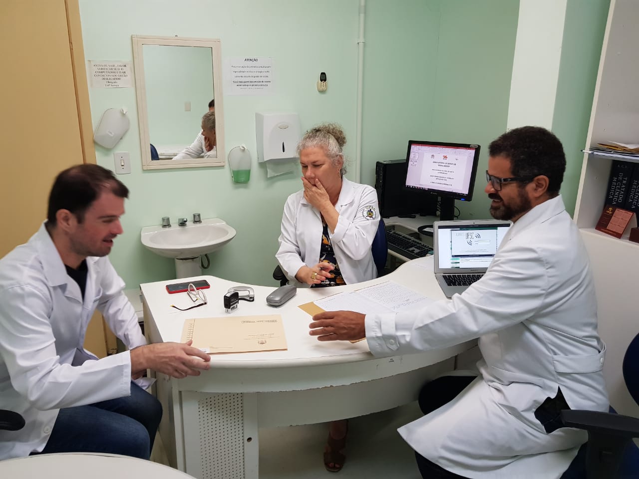 Equipe de saúde em discussão de prontuários em ambiente ambulatorial