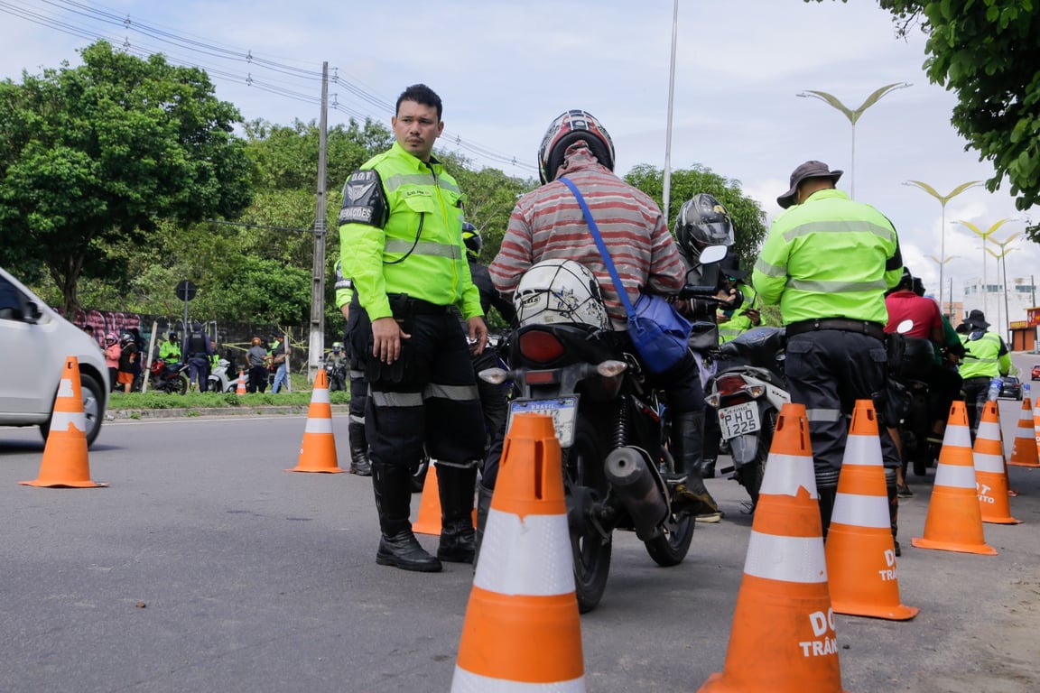 Agentes de trânsito em operação em via urbana, com cones e viatura; imagem ilustrativa de segurança viária