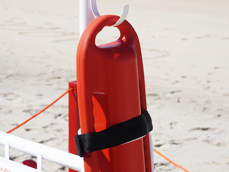 Posto de guarda-vidas com boia torpedo e bandeiras de sinalização, visto da praia