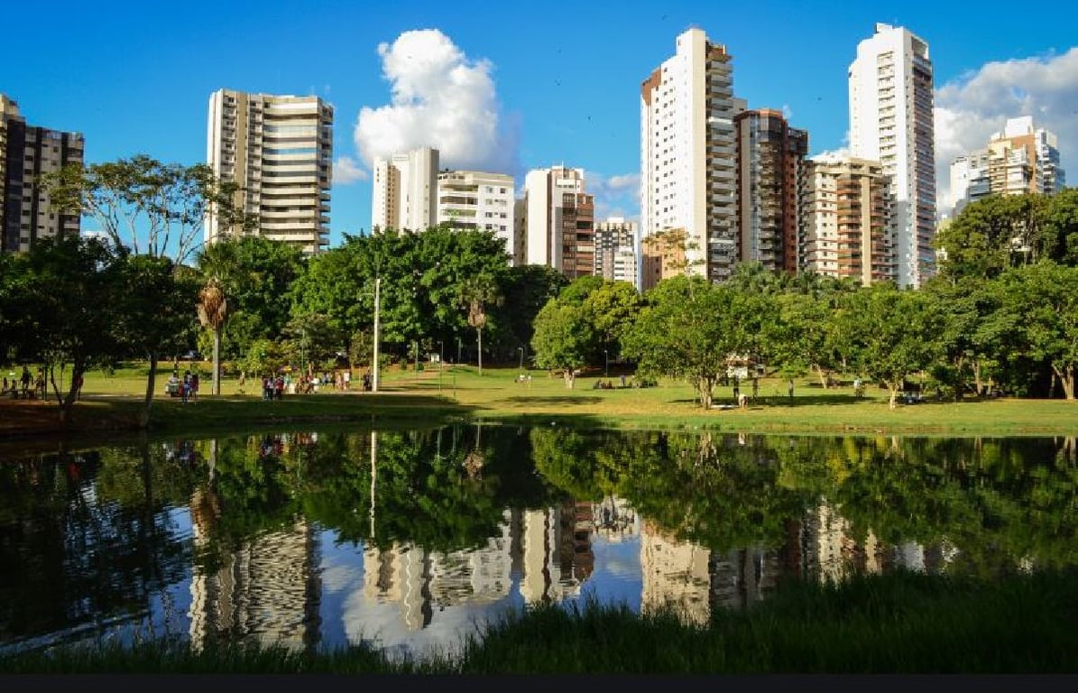 Skyline de Goiânia refletida em lago ao pôr do sol