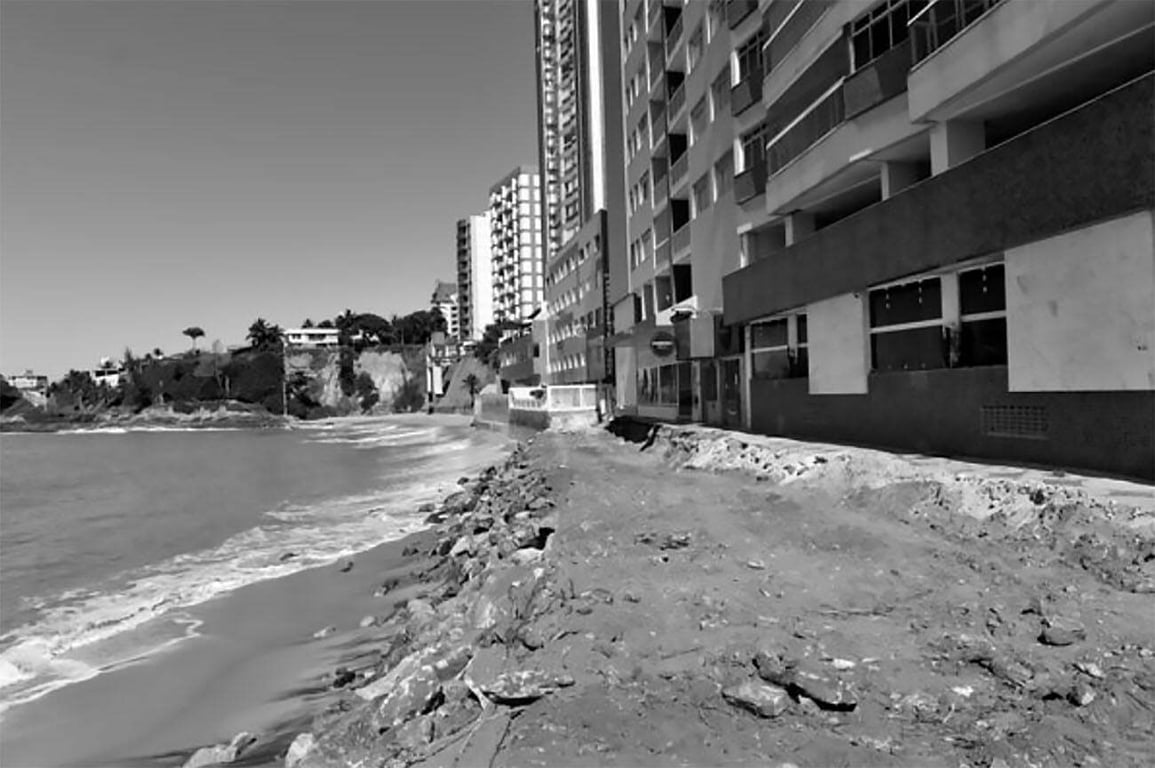 Orla urbana de Guarapari ES, com faixa de areia e prédios residenciais ao fundo