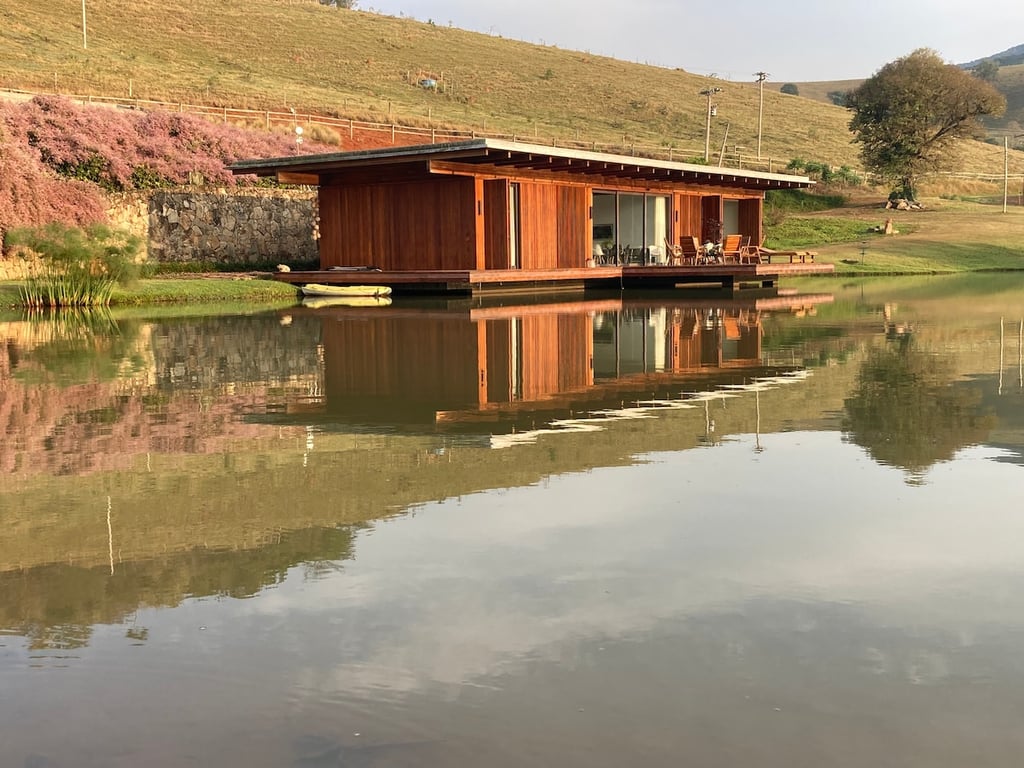 Represa em Piracaia (SP) ao entardecer, com morros ao fundo e vegetação