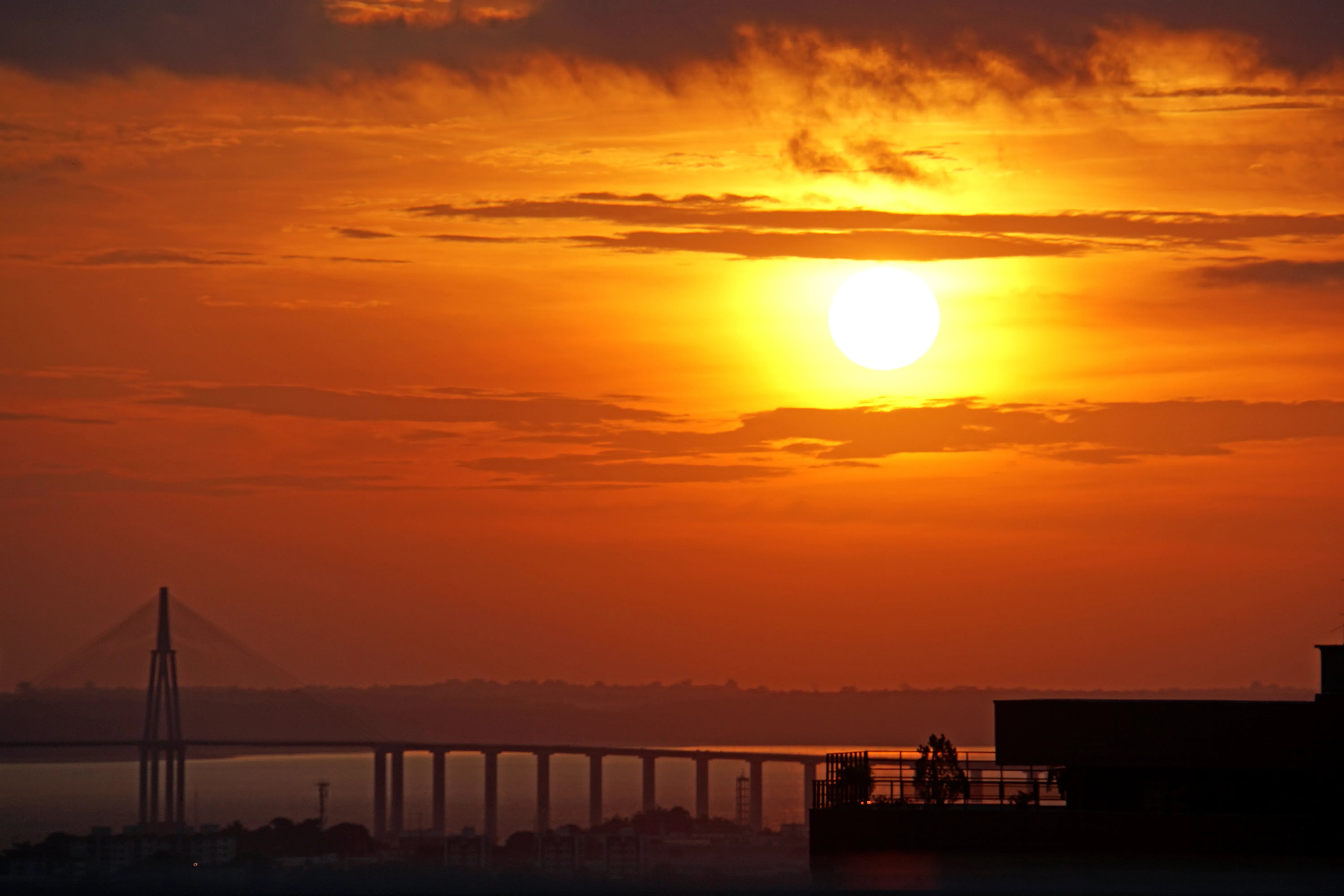 Vista aérea de Manaus ao pôr do sol, com a ponte e o rio Negro ao fundo