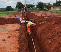 Obras de infraestrutura de saneamento, com equipe em campo e instalação de tubulações em área urbana