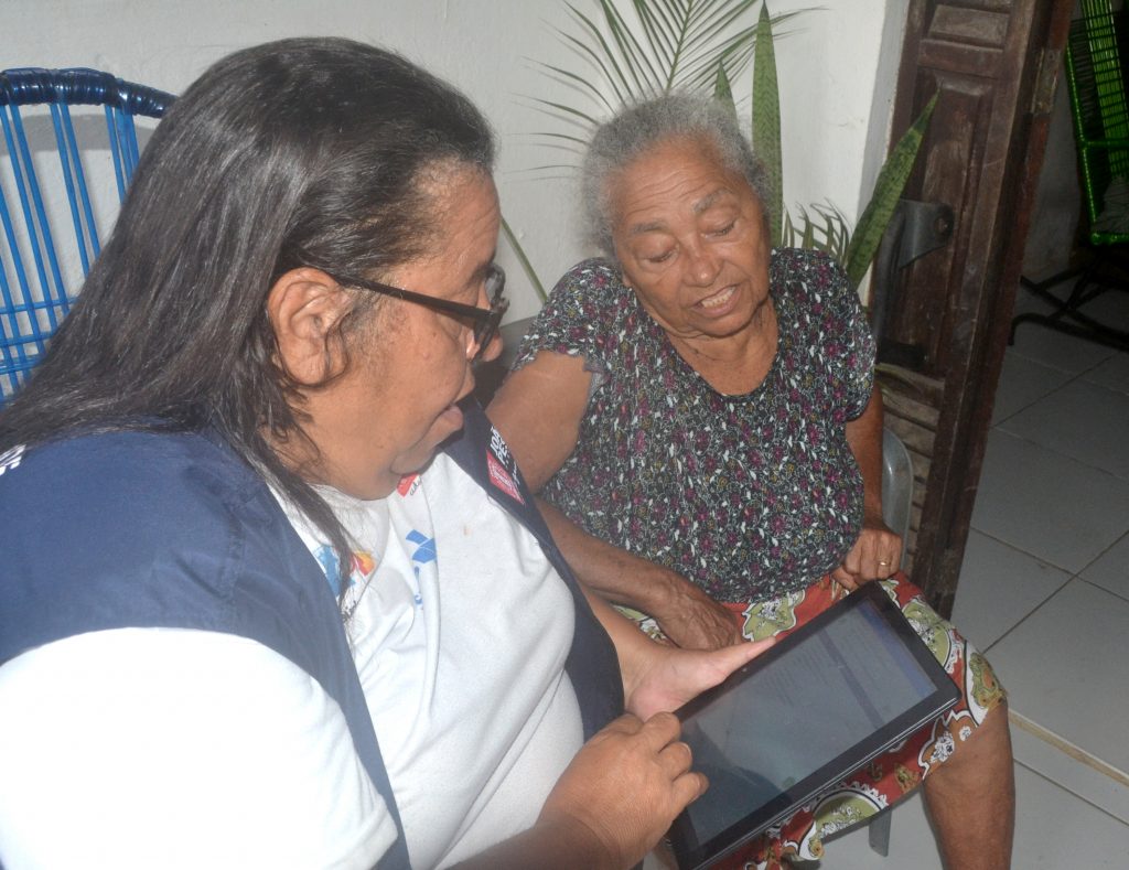 Agente comunitária de saúde em visita domiciliar com tablet