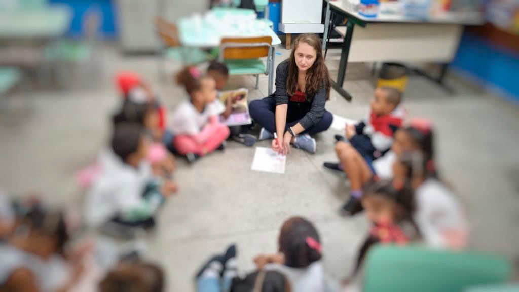 Sala de aula da educação básica com professora e crianças em atividade pedagógica