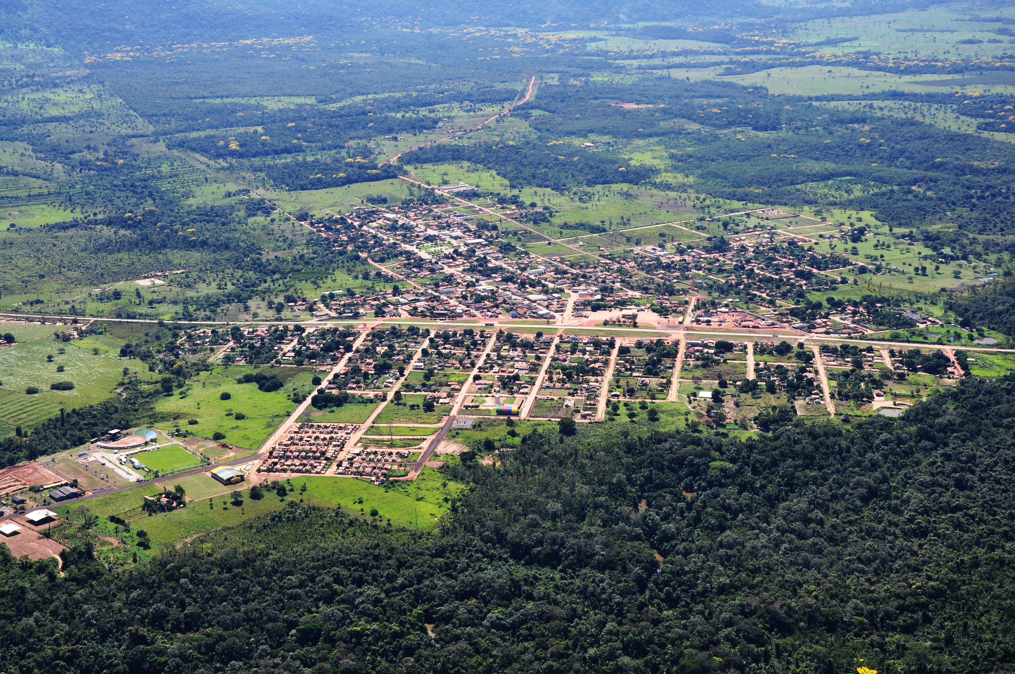 Vista aérea de cidade do interior de Mato Grosso, com ruas arborizadas e chapadas no horizonte