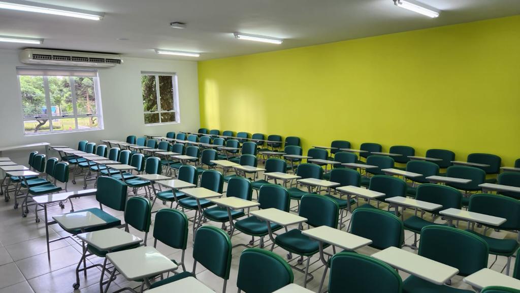 Sala de aula de ensino superior, com carteiras e iluminação natural