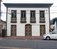 Museu de Itabira em dia nublado, com a fachada histórica e rua adjacente ao fundo.