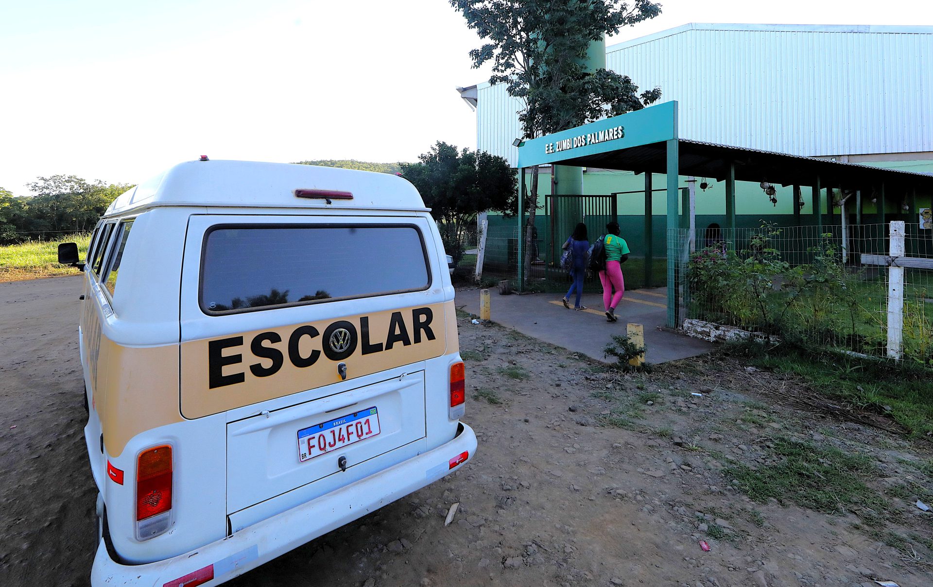Entrada de escola municipal rural com estudantes chegando
