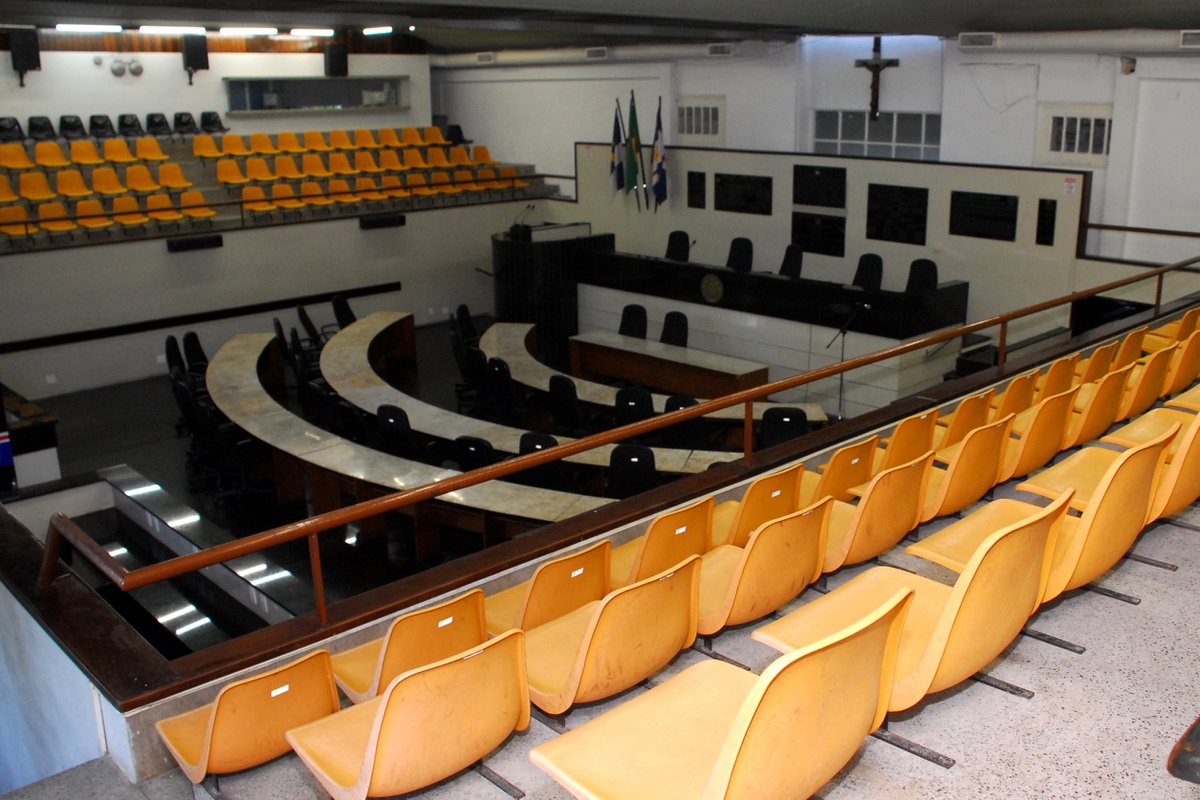 Plenário de câmara municipal brasileira, com mesas e microfones