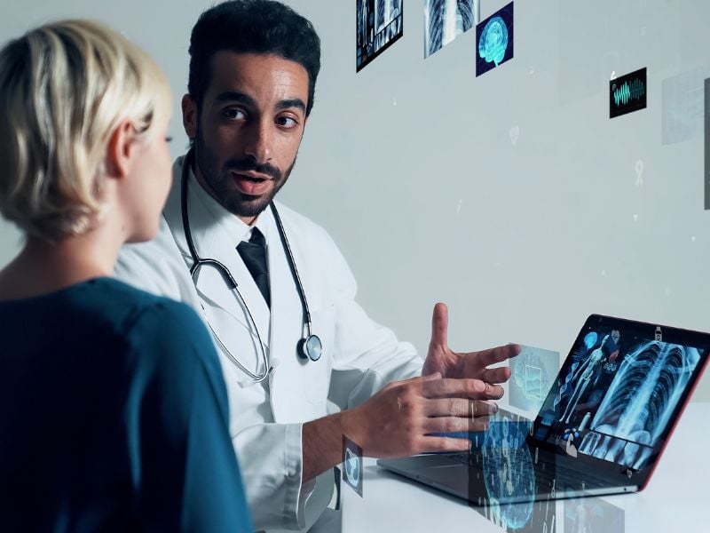 Cenário de telemedicina com médico diante de monitores explicando gráficos de saúde