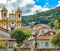 Vista urbana de Itambacuri MG, com a igreja matriz em destaque e morros ao fundo.