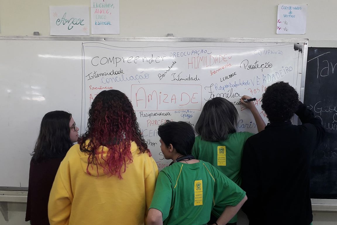 Sala de aula brasileira, com professor(a) e estudantes em atividade na lousa