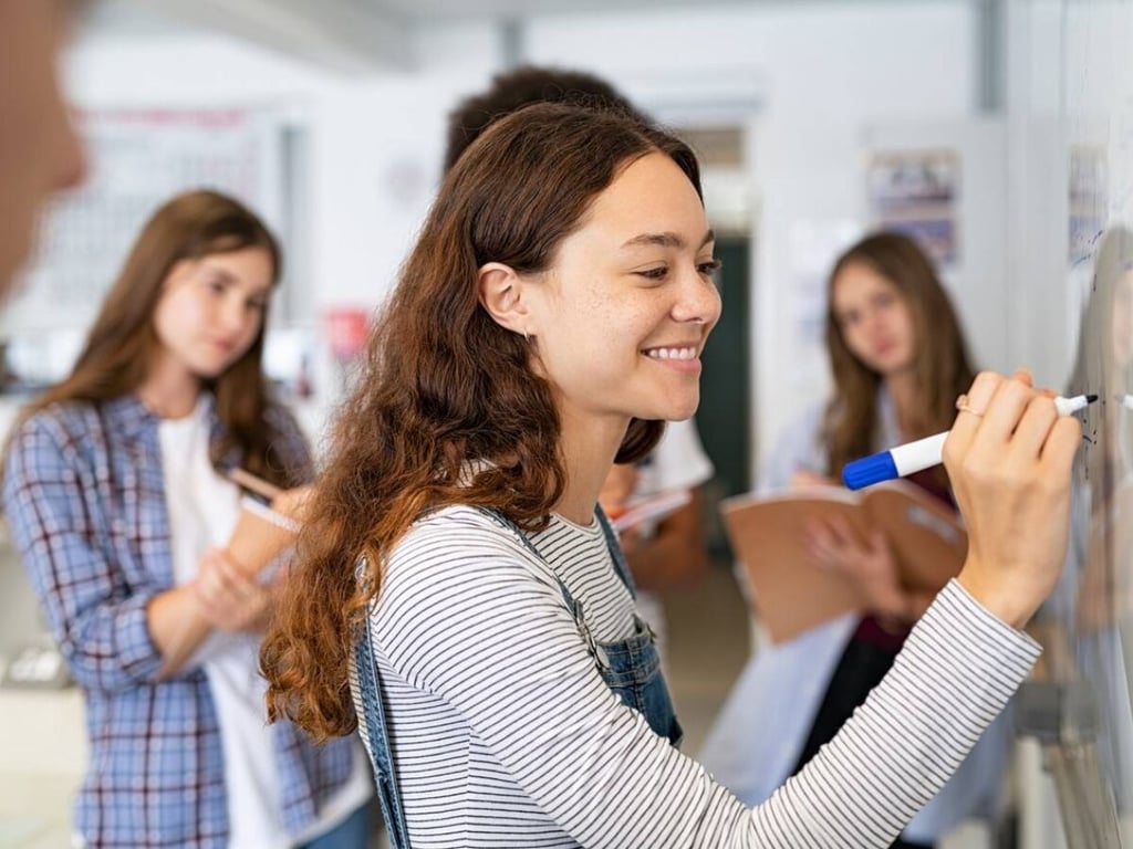 Professor escrevendo em quadro branco em sala do Ensino Fundamental – Anos Finais
