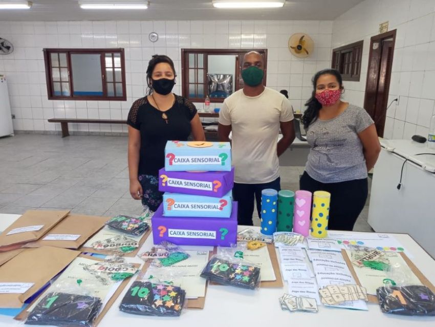 Profissionais da educação interagindo em sala de aula, com foco em inclusão e materiais pedagógicos