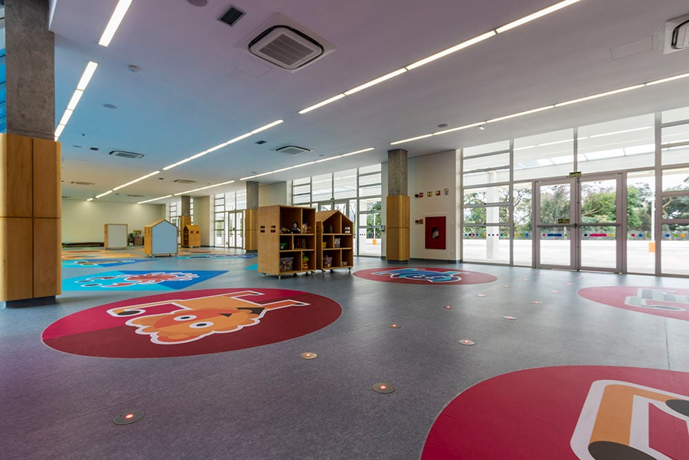 Sala de aula de escola pública com carteiras, lousa e materiais pedagógicos; ambiente iluminado e organizado