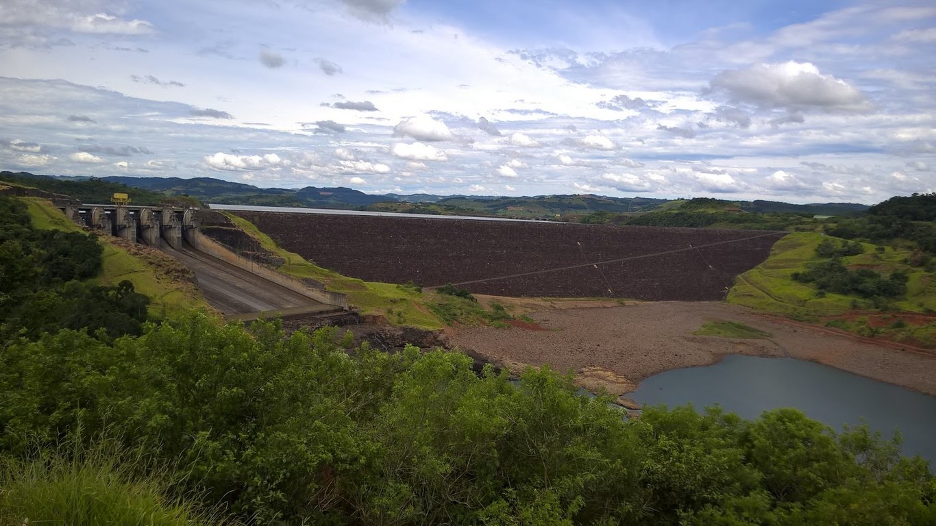 Paisagem do Rio Uruguai com represa hidrelétrica ao fundo, margens verdes e céu limpo ao entardecer
