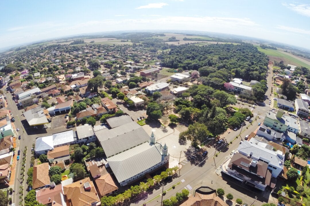 Vista aérea de Tuparendi, no Noroeste gaúcho, com área urbana, vegetação e igreja ao fundo em dia ensolarado