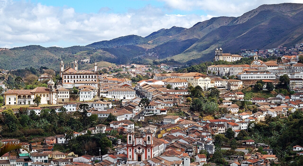 Centro urbano de pequena cidade do sertão, com praça e igrejas sob céu azul.