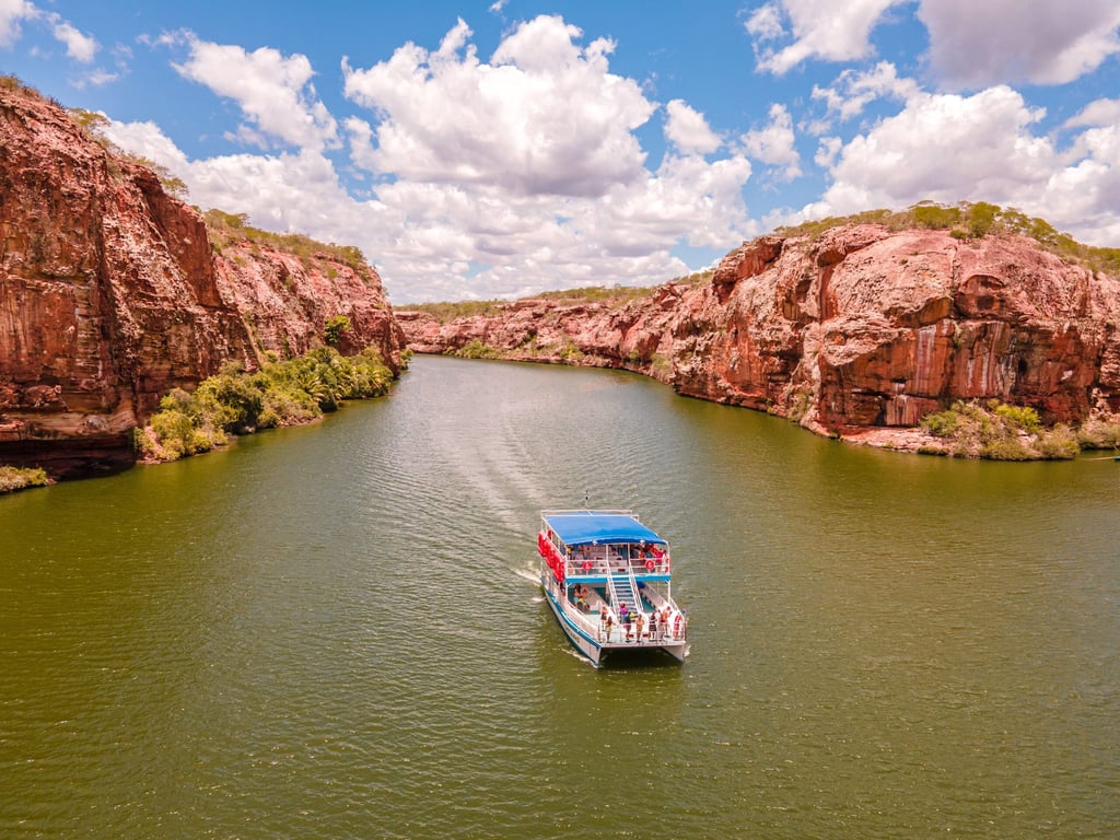 Cânion do Rio São Francisco em Piranhas AL ao entardecer, com paredões rochosos e barco de passeio ao centro, em composição horizontal ampla.